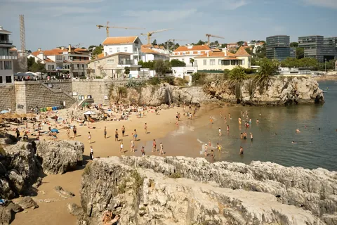 A lively beach scene in Cascais, Portugal with people enjoying the sun and sea.
