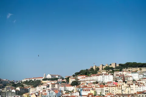 Lisbon cityscape and hillside neighbourhoods under a clear blue sky